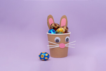 bunny craft from a paper cup filled with chocolate eggs in foil, holiday activity for kids