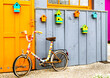 Façade d'une cabane en bois colorée et décorée de nichoirs, avec un vieux vélo vintage customisé au tricot appuyé sur la porte. Île d'Oléron.