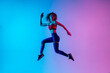 © master1305 - High jump. Beautiful woman in bright sportwear isolated on gradient pink-blue background in neon light. Athletic and graceful. Modern sport, action, motion, youth concept. Sportive female practicing
