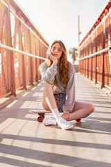 Wall Mural - Skater girl sitting on a skateboard. Portraits of a young woman with a longboard