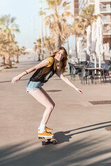 Wall Mural - Skater girl riding a long board skate. Cool female urban sports. California style outfit. Woman on skateboard wearing pink glasses