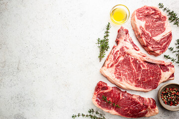 Wall Mural - Variety of Fresh Raw Black Angus Prime Meat Steaks T-bone, New York, Ribeye and seasoning on white background, top view