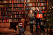 © shunevich - Overjoyed family with little son stand near Christmas tree, caring parents with joyful kid hold presents in arms, smiling, enjoy winter holidays, new year celebration concept