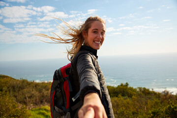 POV Shot Of Young Woman Hiking In Countryside By Sea Encouraging Partner To Follow Her