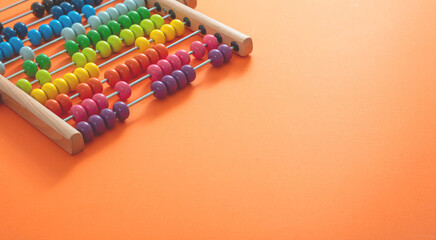School abacus with colorful beads on orange color background, close up view
