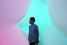 Man Standing Amidst Balloons In Art Gallery