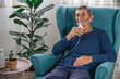 © perfectlab - elderly senior sits in a armchair with an oxygen mask in quarantine at home