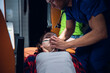 © Anna Kosolapova - Paramedic presses an oxygen mask to a woman's face, who is lying on a stretcher in an ambulance car.