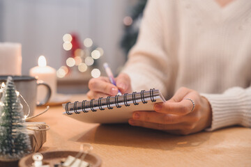 Goals plans make to do and wish list for new year christmas concept writing in notebook. Woman hand holding pen on notepad at home on winter holidays xmas.