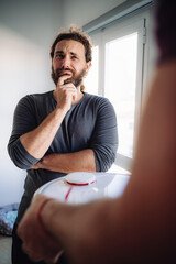 Bearded man react unsure about a smart robot showed by his friend