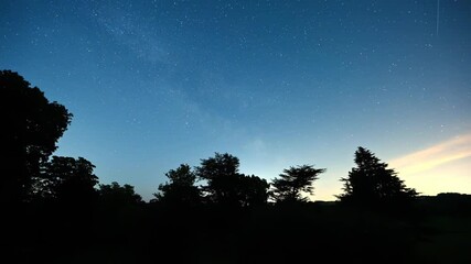 Timelapse of a push through a silhouette window to reveal stars in a clear night sky and dark trees in the foreground