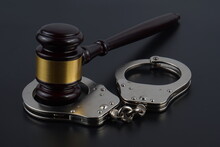 Close-up Of Handcuffs With Gavel On Black Table
