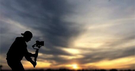 Wall Mural - Time lapse: Silhouette of videographer is filming with cinema gimbal video dslr at sunset , professional video, videographer in events. Cinema lens on gimbal. Medium shot from right side