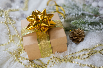 beautiful golden gift box with a bow on the snow for the new year and christmas with decorations and a christmas tree