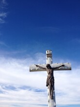 Low Angle View Of Crucifix Against Blue Sky