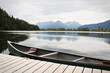 Side view of canoe tied to a dock with mountains in the background