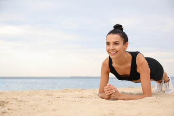 Poster - Young woman doing plank exercise on beach, space for text. Body training