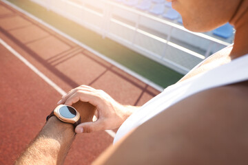 Poster - Man checking fitness tracker after training at stadium, closeup