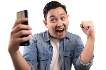 Wall Mural - Attractive young Asian man have good news on his phone, happy laughing winning expression