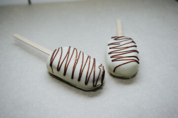 Wall Mural - delicious cake like ice cream on a stick in icing and chocolate on a napkin