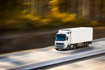 White truck with white trailer on the road in autumn