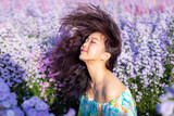 Fototapeta Lawenda - Asian happy woman flick hair in flower dress sit in Margaret Aster flowers field. Winter travel relax vacation concept at Chiang Mai, Thailand. Soft focus
