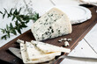 a piece of dor blue cheese on a cheese board with knives. delicacy blue cheeses. Homemade cheese making