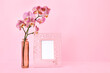 Vase with beautiful orchid flowers and blank photo frame on color background
