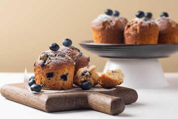 Poster - Blueberry muffins decorated with fresh blueberries and powdered sugar, without muffins cup, on white table, Selective focus. Copy space.