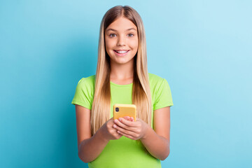 Sticker - Photo of young smiling happy cheerful good mood girl browsing online in social network isolated on blue color background