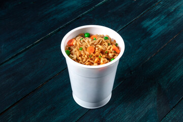 Wall Mural - Ramen cup. Instant noodles with vegetables on a dark blue background