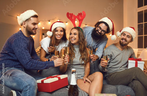 Fotografía Group of smiling friends in holiday caps and accessories feasting Christmas with