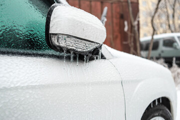 Ice covered car window close up. Car covered with ice and icicles after freezing rain. Bad winter weather, ice storm.