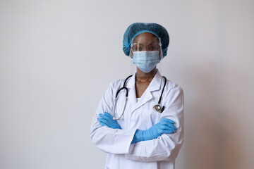 Wall Mural - Portrait of a doctor in lab coat with face mask, face shield,  and hair ppe with arms crossed