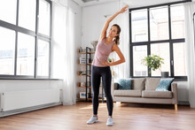 sport, fitness and healthy lifestyle concept - smiling young woman exercising at home