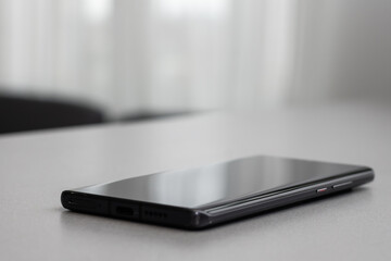 Poster - Black modern mobile phone with blank screen on black stone table background. Smartphone on old dark grey vintage texture background.
