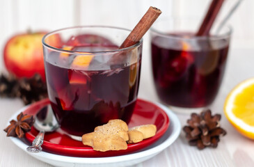 side view of two traditional winter hot alcohol cocktails in transparent glasses, a pair of christmas homemade mulled wine or grog or punch on white wooden table