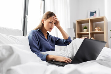 Poster - technology, internet and people concept - stressed young woman with laptop computer in bed at home bedroom