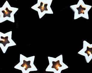 New Year and Christmas frame of lightning garland made of wooden white stars on black background.