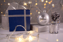 Christmas Composition. Blue Christmas Gifts, Silver Decoration: Ball, Ribbon, Cone, Drum And Golden Lights. Front View