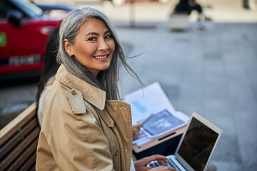Beautiful woman using modern laptop on the street