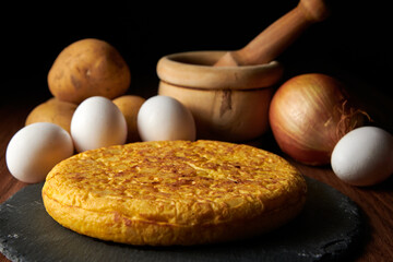 Wall Mural - A closeup of a fresh tasty Spanish omelette and the ingredients on the background, a traditional dish from Spain