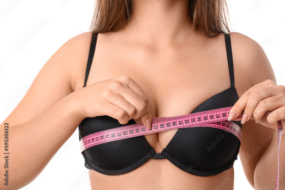 Young woman measuring her breast on white background