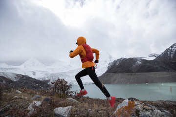 Woman trail runner cross country running  in winter mountains