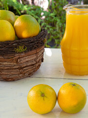 Oranges and orange juice on an old white table with blurred nature in the background, natural light, selective focus.