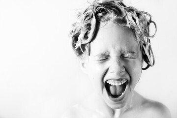 Wall Mural - a little blonde girl in the bathroom with foam on her head laughs happily with her mouth open