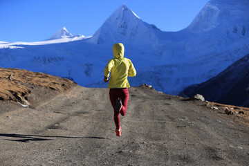 Woman trail runner cross country running  in winter mountains