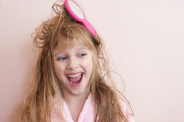 little girl brushes her tangled hair after a shower