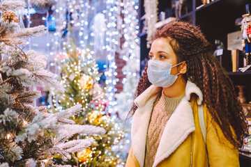 Beautiful afro haired woman wearing protective medical face mask in christmas decorated shop