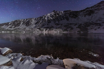 Wall Mural - Starry sky in winter Polish Tatras near a mountain lake covered with ice